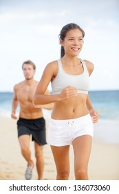 Running Couple. Woman Fitness Runner Smiling Happy During Jogging Exercise Outside On Beach With Male Fitness Sport Model. Multiracial Couple, Asian Female Model And Caucasian Man Exercising Together.