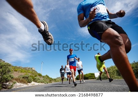 Running fast and free. Low angle shot of a group of young men running a marathon.