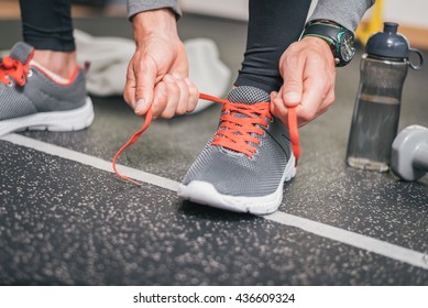 Running footwear close up. Gym indoor workout and fitness healthy concept. Male athlete tying sport shoes laces before training.