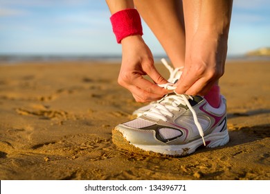 Running and jogging exercising concept. Woman tying laces before training on beach. Unrecognizable caucasian girl wearing sport shoes. - Powered by Shutterstock