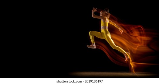 Running, Jumping. Young Woman, Female Professional Athlete In Motion Isolated Over Black Studio Background In Mixed Neon Lights With Copy Space For Ad. Concept Of Sport, Healthy Lifestyle, Motion.