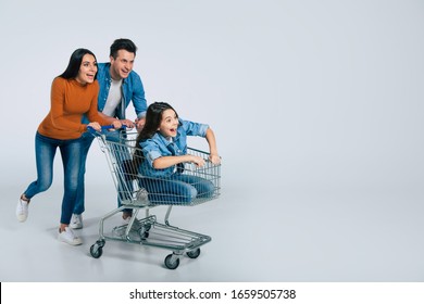 Running and laughing. Full-length photo of a family goofing around together, laughing and running while riding a small excited kid in a shopping cart.
