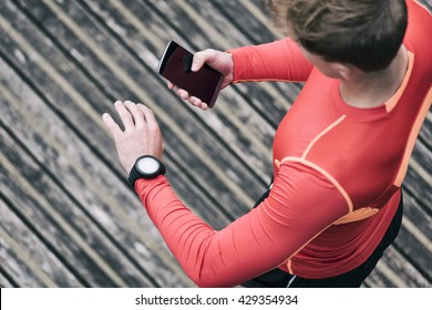 Running Man Checking Sport Performance On His Mobile Phone And Smartwatch App