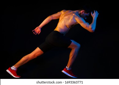 Running Man. Run In Motion On Black Background With Colorful Lights. Dynamic Movement. Runner Using Starting Block To Start His Run On Running