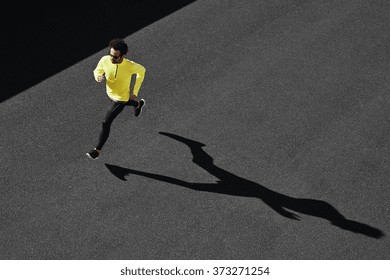 Running Man Sprinting For Success On Run. Top View Athlete Runner Training At Fast Speed At Asphalt. Muscular Fit Sport Model Sprinter Exercising Sprint In Yellow Sportswear. Caucasian Fitness Model