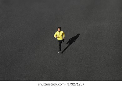 Running Man Sprinting For Success On Run. Top View Athlete Runner Training At Fast Speed At Asphalt. Muscular Fit Sport Model Sprinter Exercising Sprint In Yellow Sportswear. Caucasian Fitness Model