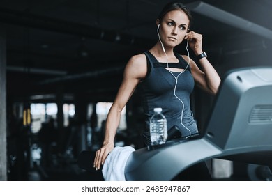 Running, music and woman on treadmill in gym listening to podcast, audio and radio for cardio workout. Sports, wellness and person with earphones for exercise, marathon training and fitness for race