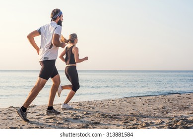 Running people - woman and man athlete runners jogging on beach. Fit young fitness couple exercising healthy lifestyle outdoors during sunrise or sunset - Shutterstock ID 313881584