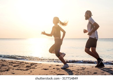 Running people - woman and man athlete runners jogging on beach. Fit young fitness couple exercising healthy lifestyle outdoors during sunrise or sunset - Shutterstock ID 317714849