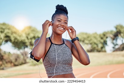 Running, portrait of woman on track with headphones and phone for fitness app on happy workout. Technology, sports and black woman runner with smile streaming music on run for health and wellness. - Powered by Shutterstock