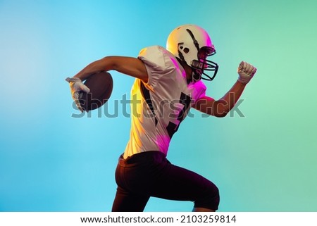 Running. Power and speed. Portrait of male american football player playing, training isolated on blue background in neon light. Concept of sport, movement, achievements. Copy space for ad