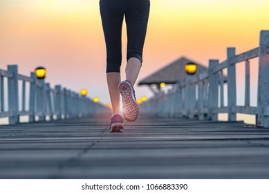 running shoe of women jogging along on the wooden bridge on regular daily exercise at sunset in the sea - Shutterstock ID 1066883390