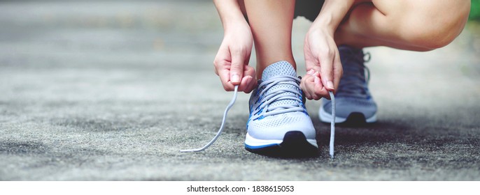 Running shoes. close up female athlete tying laces for jogging on road. Runner ties getting ready for training. Sport lifestyle. copy space banner. - Powered by Shutterstock