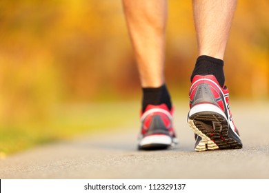 Running Shoes Closeup. Runner On Road In Fall Autumn Colors - Closeup Of Male Running Walking Shoes Of Jogger Outdoors.