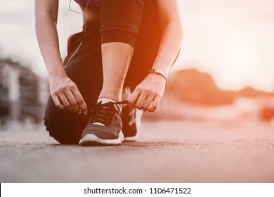 Running shoes - closeup of woman tying shoe laces. Female sport fitness runner getting ready for jogging outdoors on way