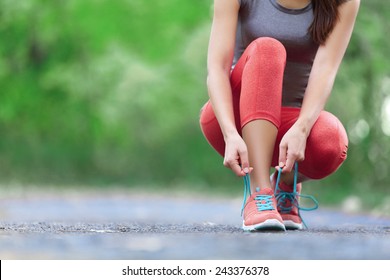 Laufschuhe - Nahaufnahme von Frauen, die Schuhlacke binden. Weibliche sportliche Fitness-Läufer bereit für Joggen draußen auf Waldpfad im Frühling oder Sommer.