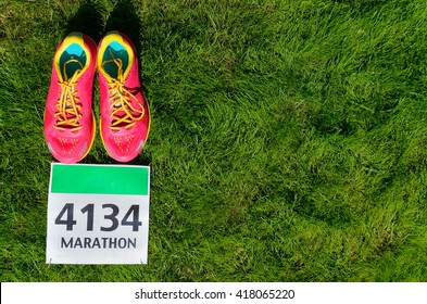 Running Shoes And Marathon Race Bib (number) On Grass Background, Sport, Fitness And Healthy Lifestyle Concept
