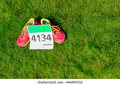 Running Shoes And Marathon Race Bib (number) On Grass Background, Sport, Fitness And Healthy Lifestyle Concept
