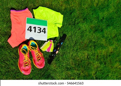 Running Shoes, Marathon Race Bib (number), Runners Gear And Energy Gels On Grass Background, Sport, Fitness And Healthy Lifestyle Concept
