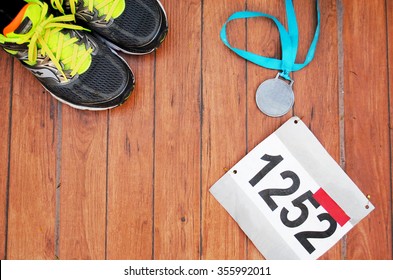 Running Shoes, Race Bib And A Medal After An Excellent Athletic Competition 