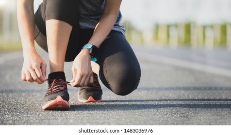 Running shoes runner woman tying laces for autumn run in forest park. Runner trying running shoes getting ready for run. Jogging girl exercise motivation heatlh and fitness.