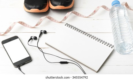 running shoes,measuring tape,drinking water,notebook and phone on white wood table - Shutterstock ID 345554792