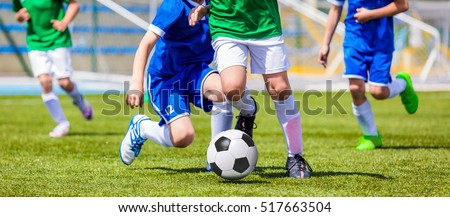 Running Soccer Football Players. Footballers Kicking Football Match game. Young Soccer Players Running After the Ball. Soccer Stadium in the Background