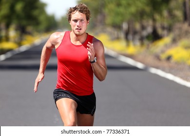 Running sport man. Fit muscular young male runner sprinting at great speed outdoors on road.