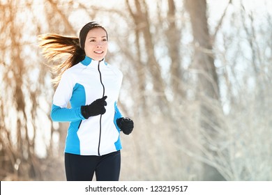 Running sport woman. Female runner jogging in cold winter forest wearing warm sporty running clothing and gloves. Beautiful fit Asian / Caucasian female fitness model. - Powered by Shutterstock