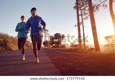 Running at sunrise couple exercising for marathon and workout fitness