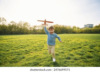 Running with toy plane. Cute happy little boy is on the field outdoors. - Powered by Shutterstock