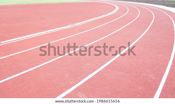 Running track in red with a carbon\
coating around the stadium with white dividing\
stripes