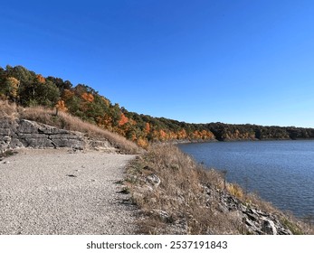 Running trail with lake and beautiful fall foliage in the background with orange and yellow leaves.  - Powered by Shutterstock