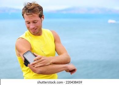 Running training music on smartphone app. Runner man listening to music adjusting settings on armband for smart phone. Fit male fitness model working outdoor by water. - Powered by Shutterstock