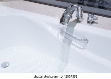 Running Water Filling Up White Bath Tub, Beige Marble Tiles.