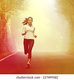 Running Woman Jogging On Road In Sunrise And Mist. Female Runner Working Out In Fall Or Winter Sports Outfit. Beautiful Multiracial Asian Caucasian Woman Athlete Outside.