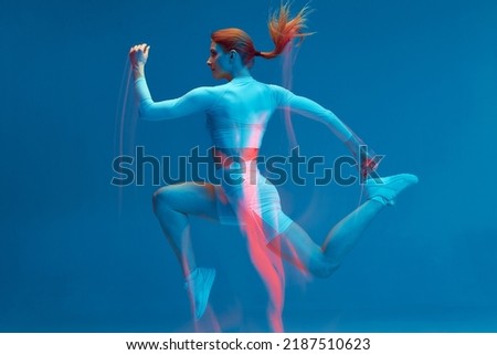 Running workout. Athlete woman runs in air on blue studio backdrop. Long exposure. Motion blur. Sports club advertising