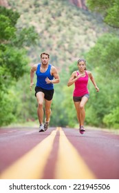 Running Young Mixed Race Couple Sprinting Concentrated On Road Outside In Nature Exercising Jogging Sport. Pretty Asian Model And Caucasian Male Model.