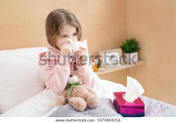 鼻水 小さな病気の女の子がベッドに横になって鼻をかむ の写真素材 今すぐ編集