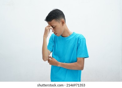 Runny nose or sinusitis concept. Asian man wearing blue t-shirt holding bridge of nose and suffering in pain