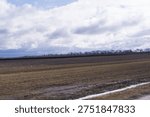 Rural agricultural fields under dramatic cloudy sky countryside farmland landscape with soil horizon and seasonal farming scene