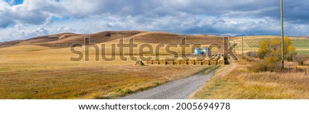 Rural Alberta Canadian prairie grassland landscape countryside background panorama. Beautiful farmer's field and grain silos with hay bales wallpaper 