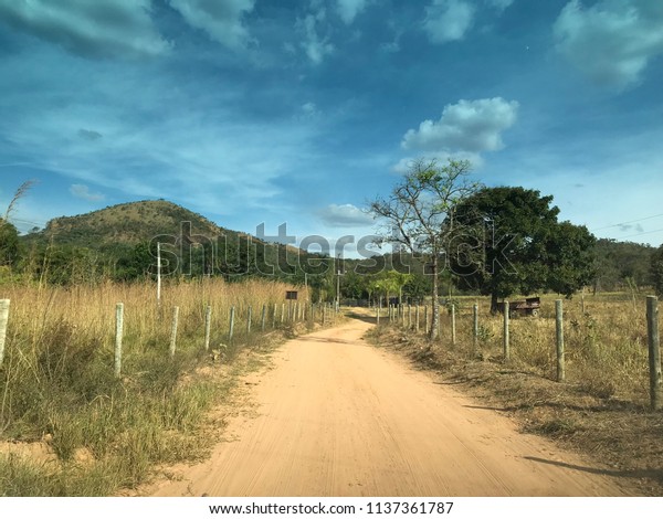 Rural area of a\
sandy dirt road, wooden fence and wire, Pirenópolis, Goiás, Brazil.\
In the Cerrado of Brazil.