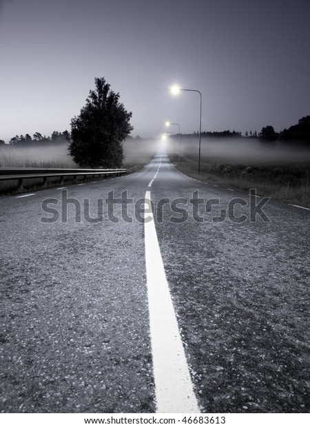 Rural asphalt road in a\
foggy evening