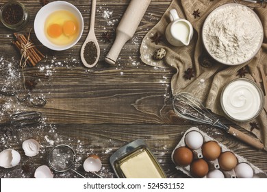 Rural Background, Cooking. Ingredients And Kitchen Items For Baking Cakes. Kitchen Utensils, Flour, Eggs, Dairy, Milk, Cream, Cooking Appliances On A Wooden Background. Chaos, Disorder. Space For Text