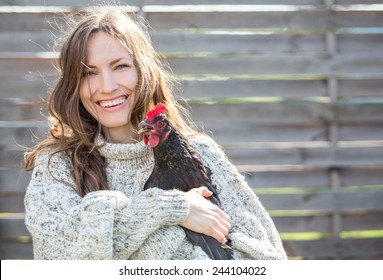 Rural beauty woman holding hen, focus on woman, daylight - Powered by Shutterstock