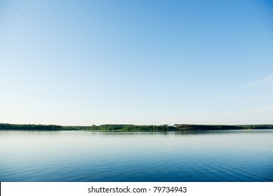 A rural blue lake and a green forest - Powered by Shutterstock