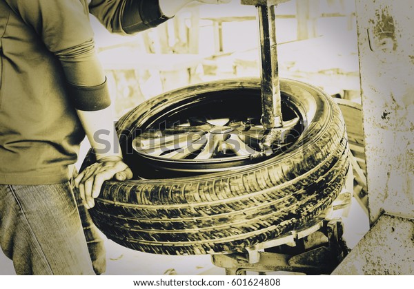 Rural car repairman in Thailand replaced tire on\
car repair. Retro style