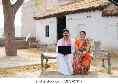 A Rural Couple Sitting On The Cot With Laptop.