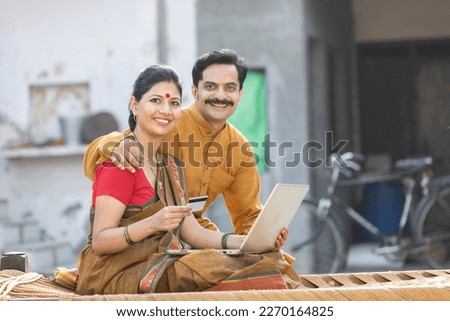 Rural couple using laptop and credit card for online banking.